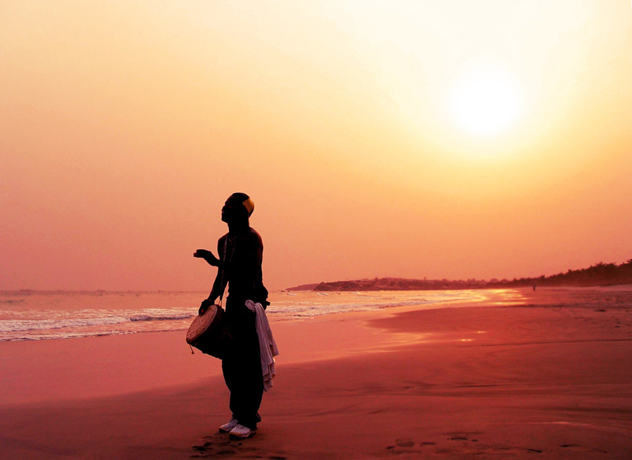 Man standing on the beach drumming