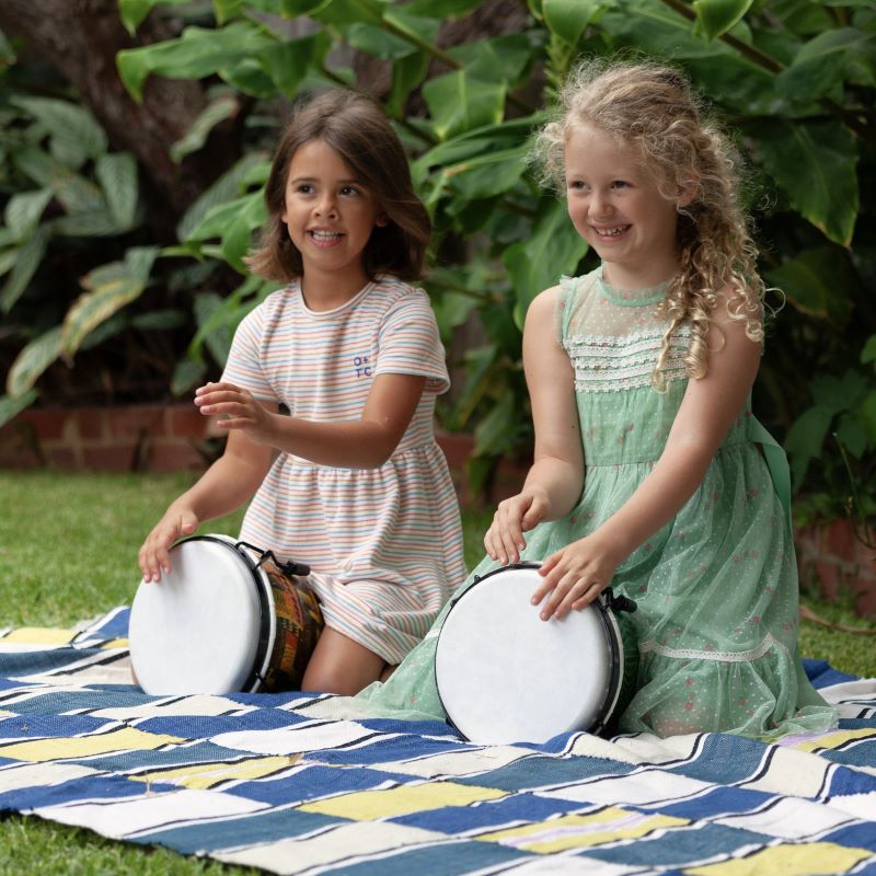 2 girls plating bongo drums outdoors