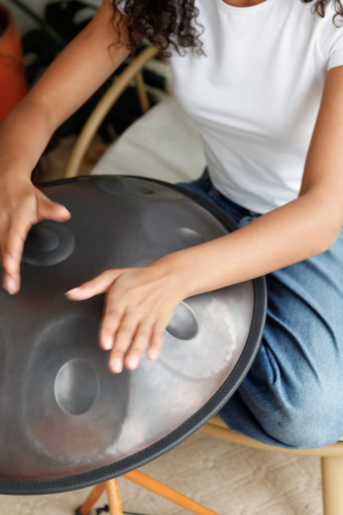 Person playing a handpan with fingertips, demonstrating a light touch technique
