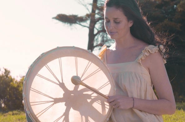 a woman playing an ancient shamanic frame drum