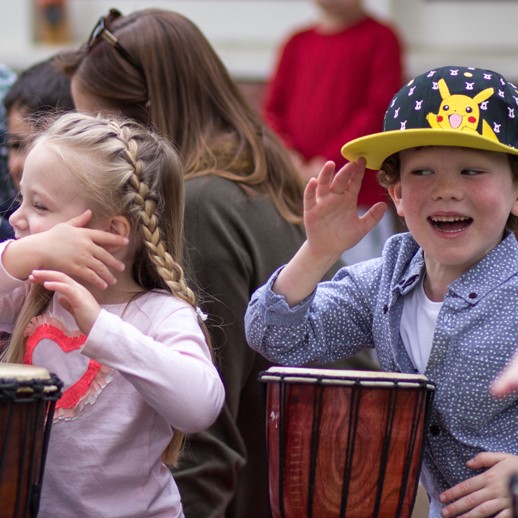 Happy kids drumming with djembes
