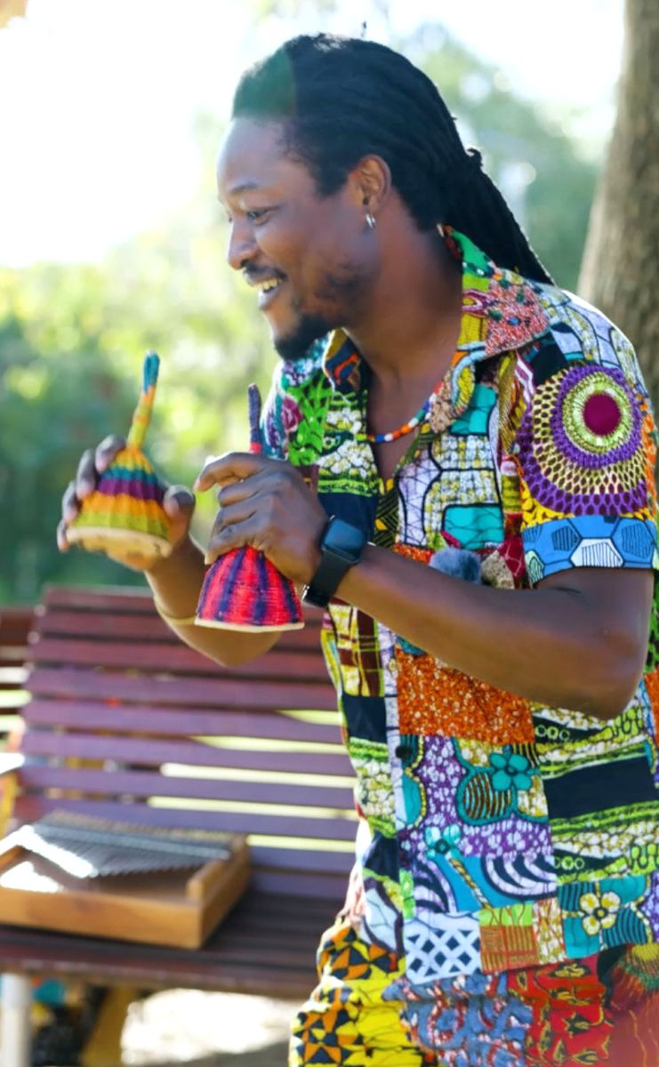 Musician holding two Ghanaian kiss kass shakers outdoors