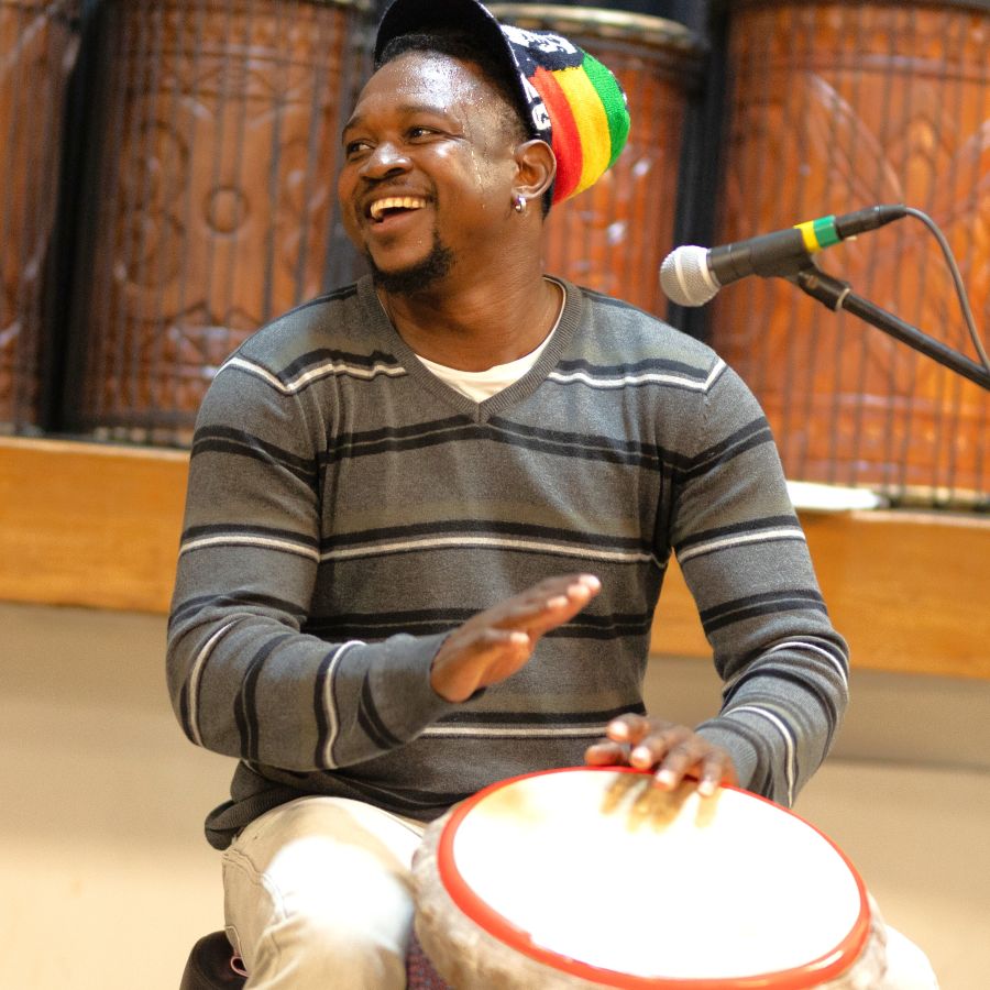 Bassidi Kone, African drumming teacher, smiling while playing djembe during a workshop