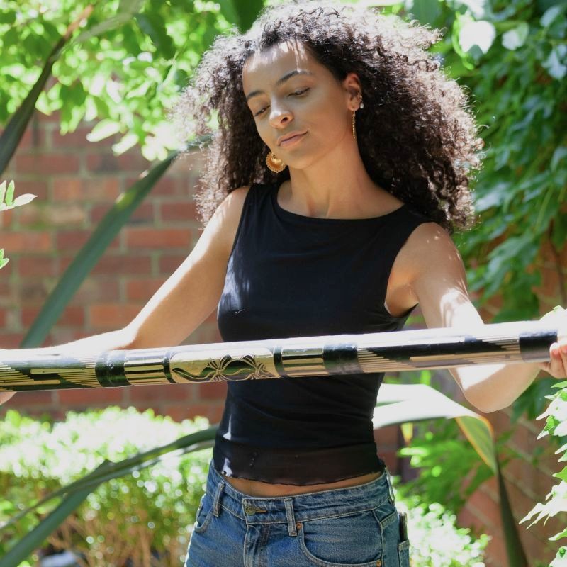 a woman holding a sound-healing rainstick made from bamboo