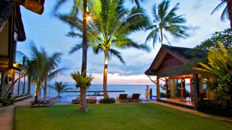 Evening view of the beachfront retreat venue for African Drumming’s Bali Drum Camp, with palm trees and soft lighting by the ocean.