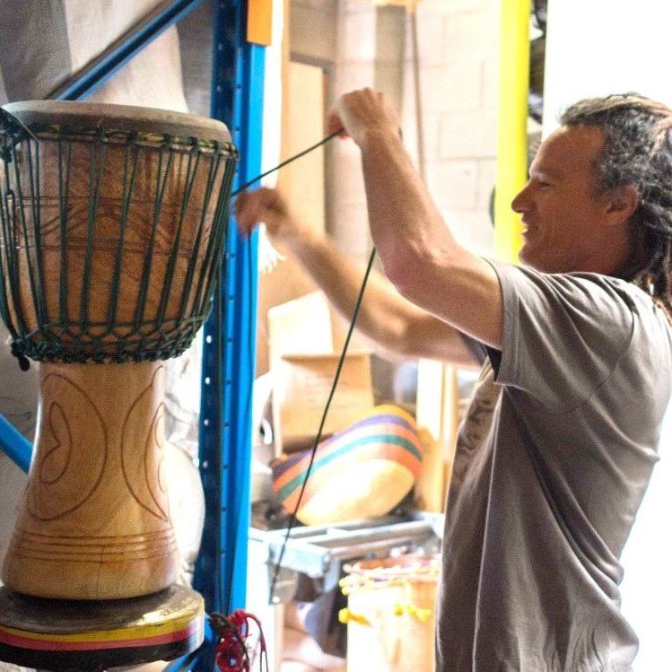 Man using rope to tighten a djembe drum at African Drumming workshop