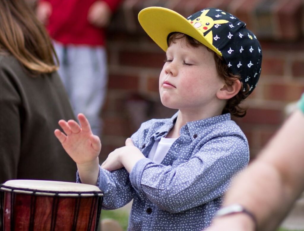 Young child playing djembe during African drumming mindfulness and wellbeing workshop for schools and kinders