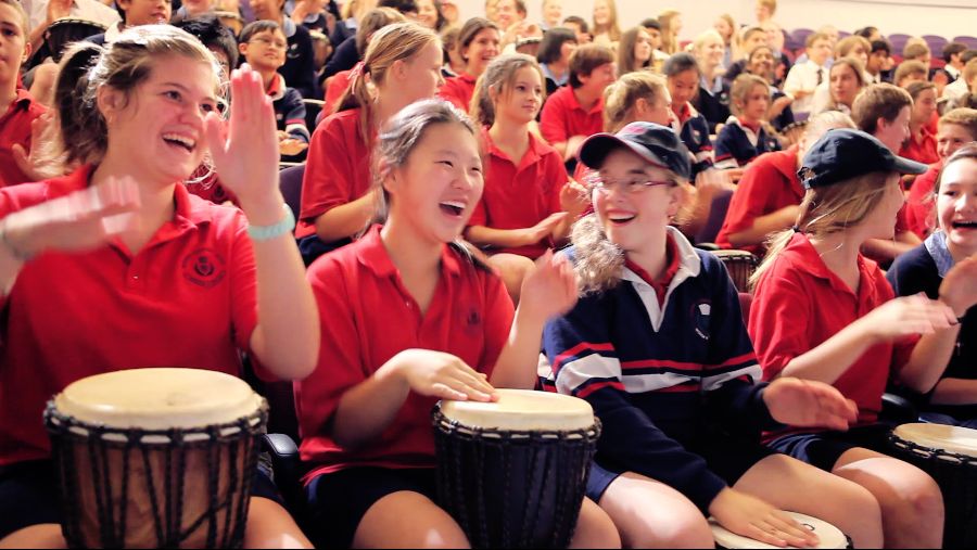 Students enjoying a school drumming workshop with African Drumming, playing djembes in a lively group session.