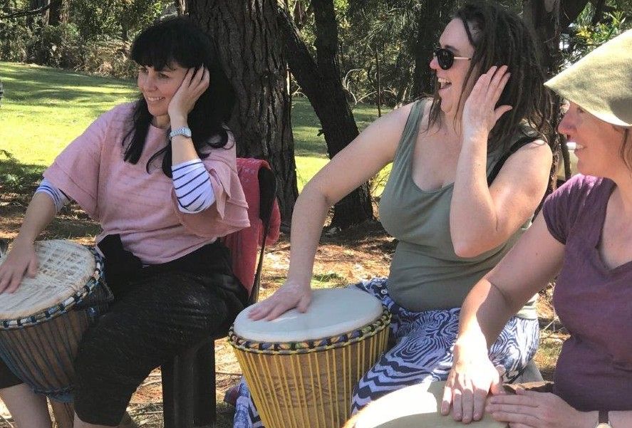 three drummers in an outdoor setting in a djembe workshop at the spring retreat
