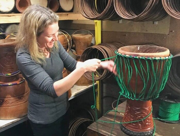 Woman learning how to rope a djembe drum at African Drumming drum making class