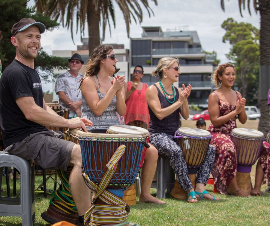 African drumming djembe class in Melbourne with group playing and clapping together outdoors