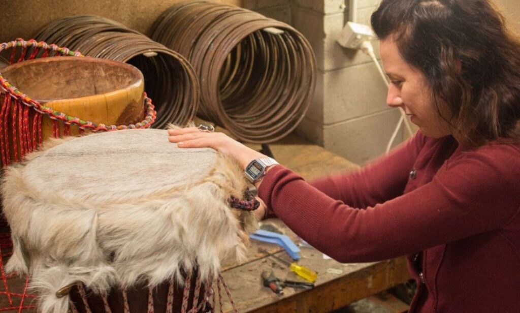a woman making a djembe in a drum making studio