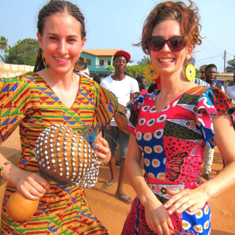Participants of the Rhythm Power Retreat in Ghana, dressed in colorful traditional attire, playing percussion instruments and enjoying a lively cultural experience.
