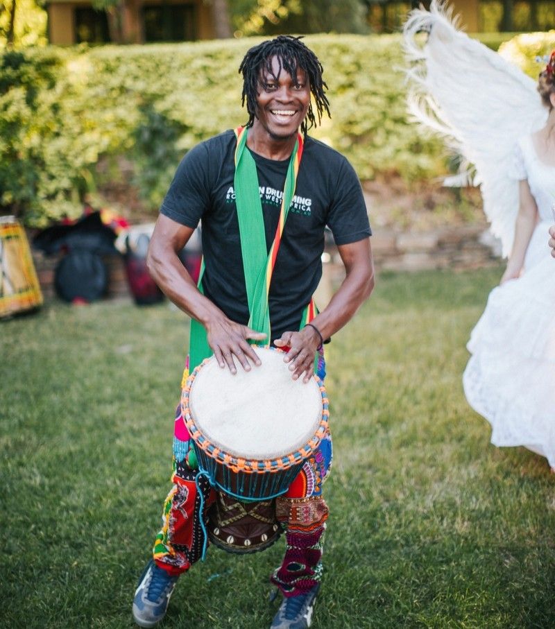 African drummer performing on djembe as live wedding entertainment outdoors