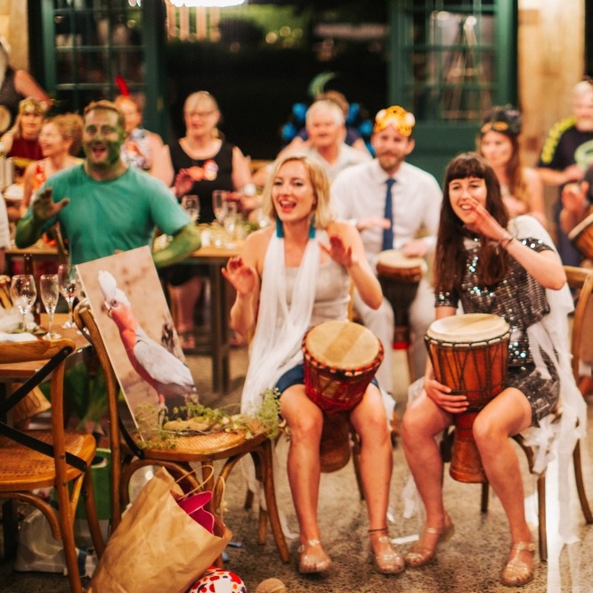 Birthday party drumming workshop with guests playing African drums in a lively group celebration