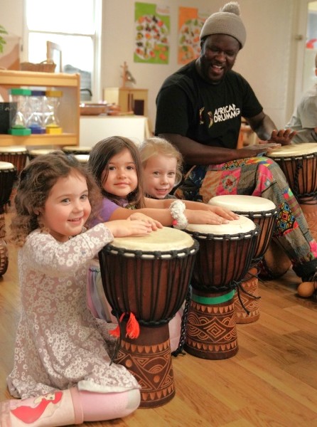 Children playing djembes with an African drumming teacher during a kindergarten incursion