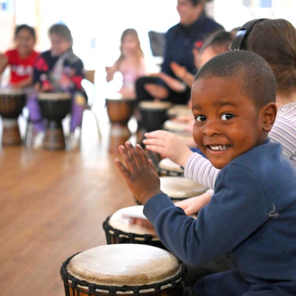 Young girl learning drumming with teacher who attended African Drumming facilitator training