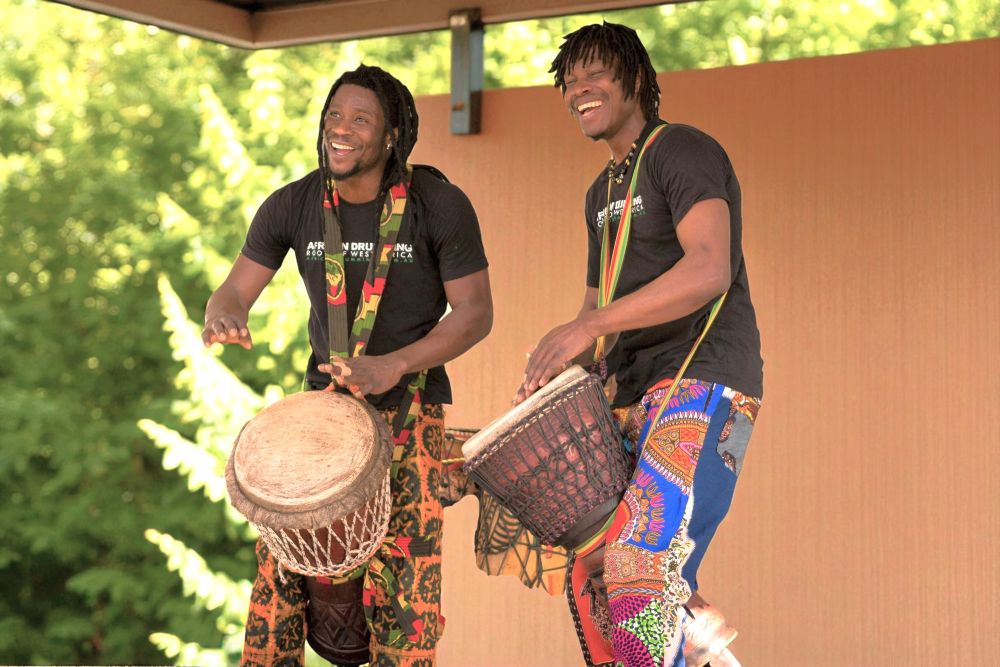Two African drummers performing live on djembe, bringing energy and rhythm to a community event