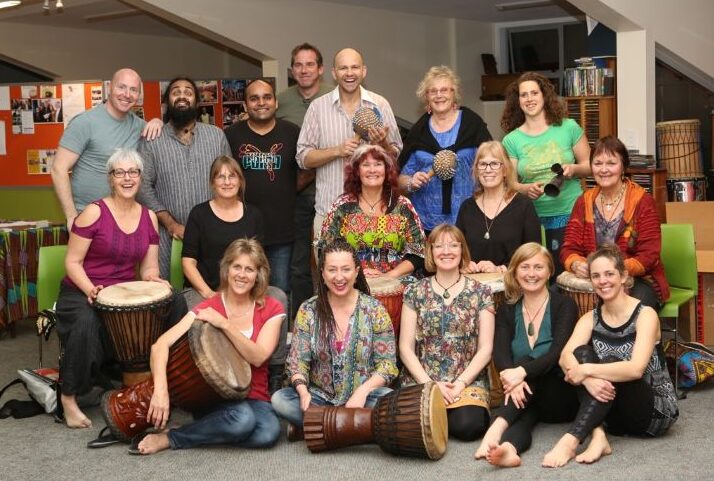 Group of adults participating in an African drumming workshop for mental health, promoting connection, wellbeing, and community support