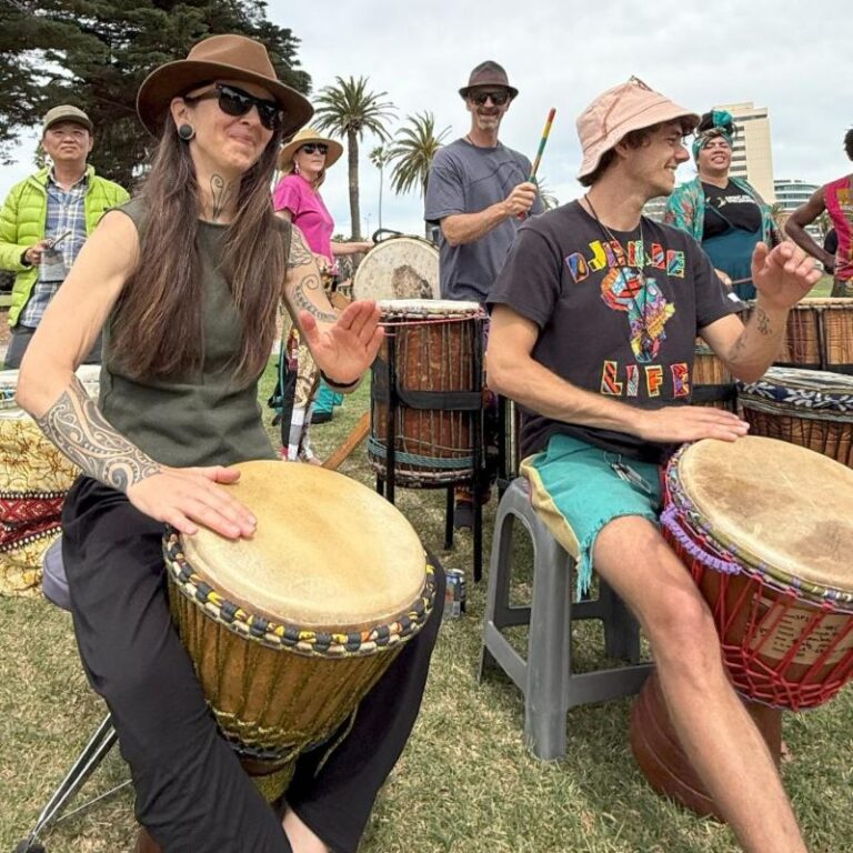 African Drumming students performing with dun dun drums in the background during class performance