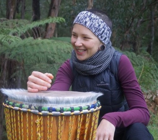 African drumming facilitator next to a djembe in the forest