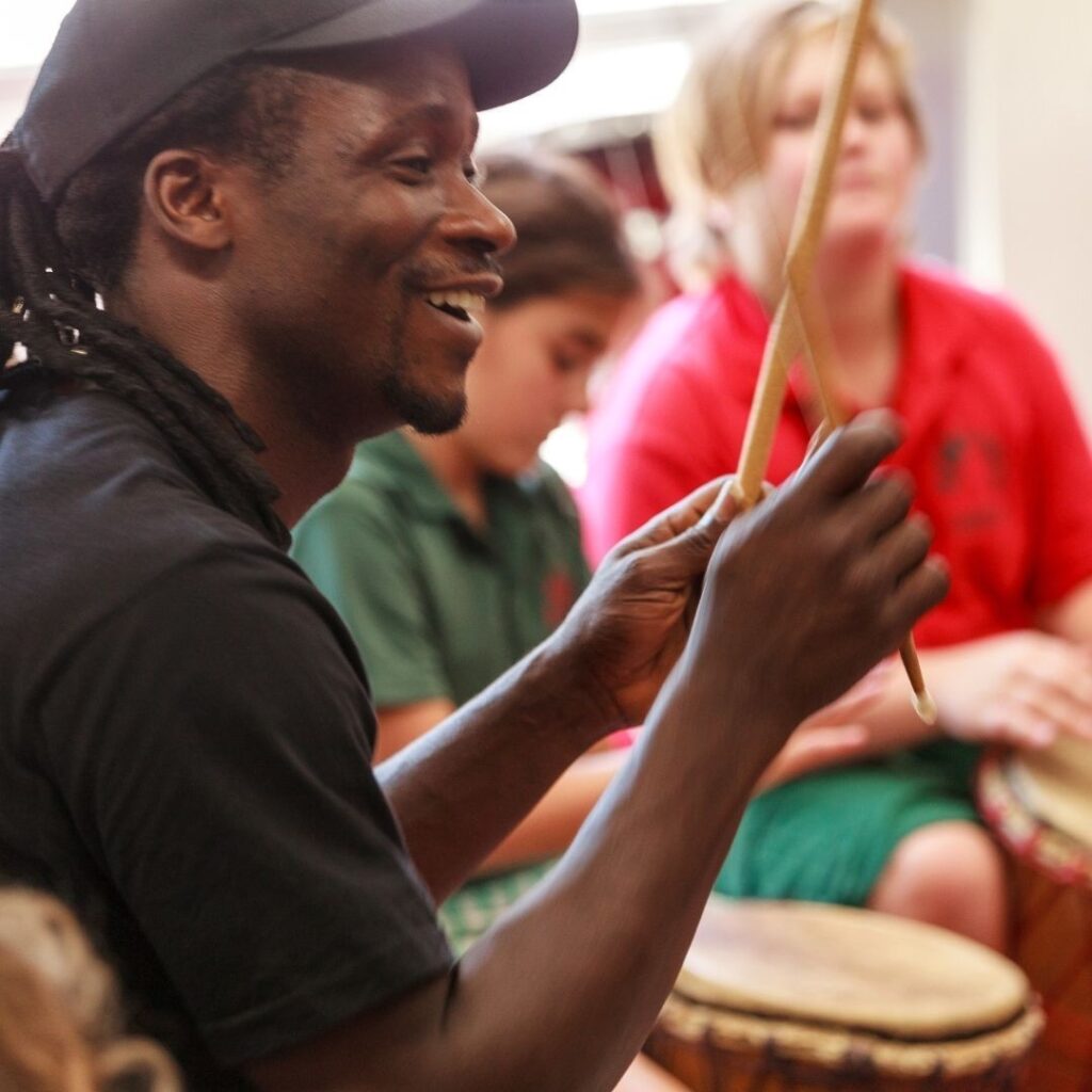 African Drumming instructor engaging with students in a hands-on drumming workshop
