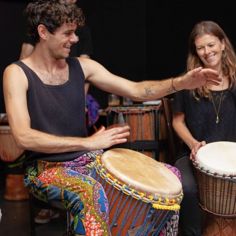 teacher and student playing djembes indoors at the student showcase event