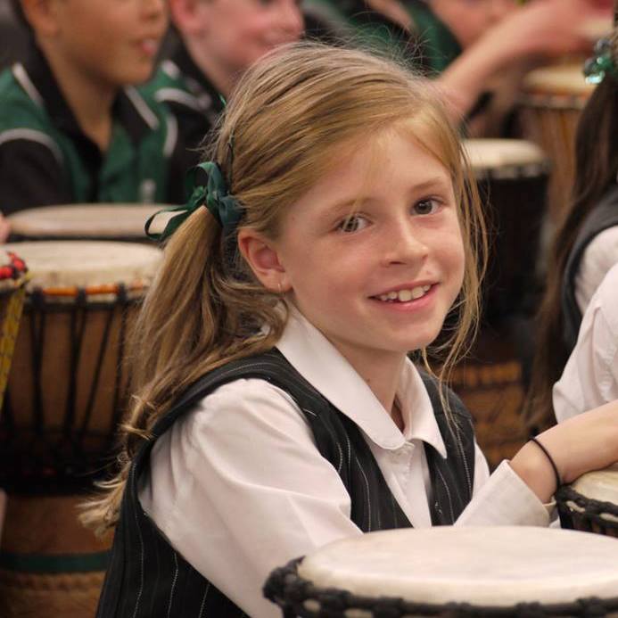 Young girl learning drumming with teacher who attended African Drumming facilitator training