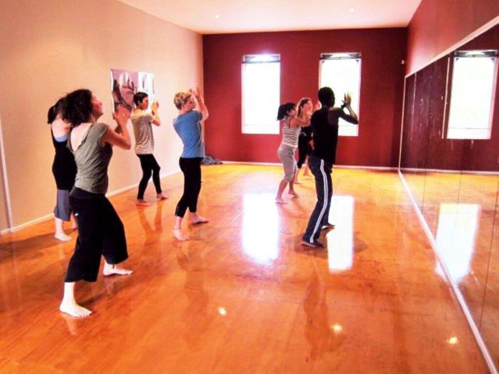 African dance class in session at the St Kilda studio with polished timber floors and mirrored wall, led by an instructor from African Drumming.