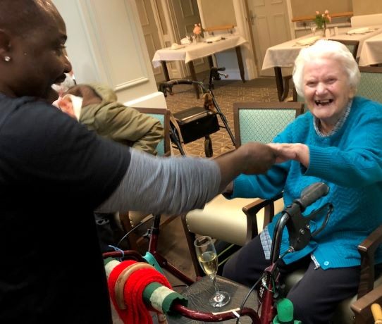an old lady dancing with an african drumming performer at an aged-care session