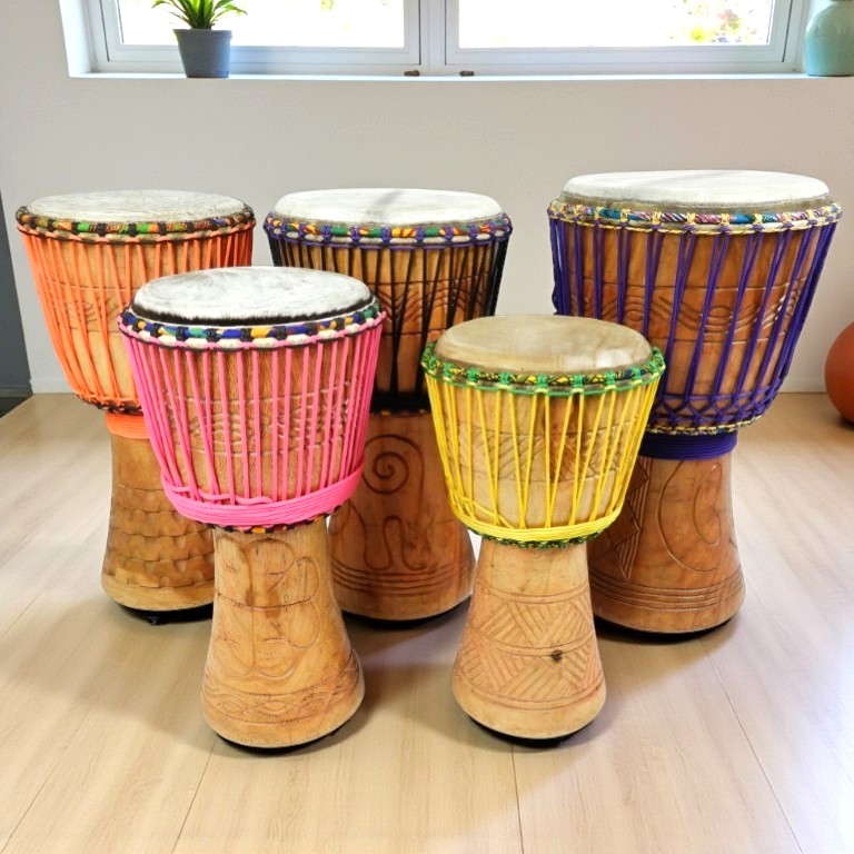 Five Ghana Series djembes with colourful rope tuning and carved shells, handcrafted in West Africa.