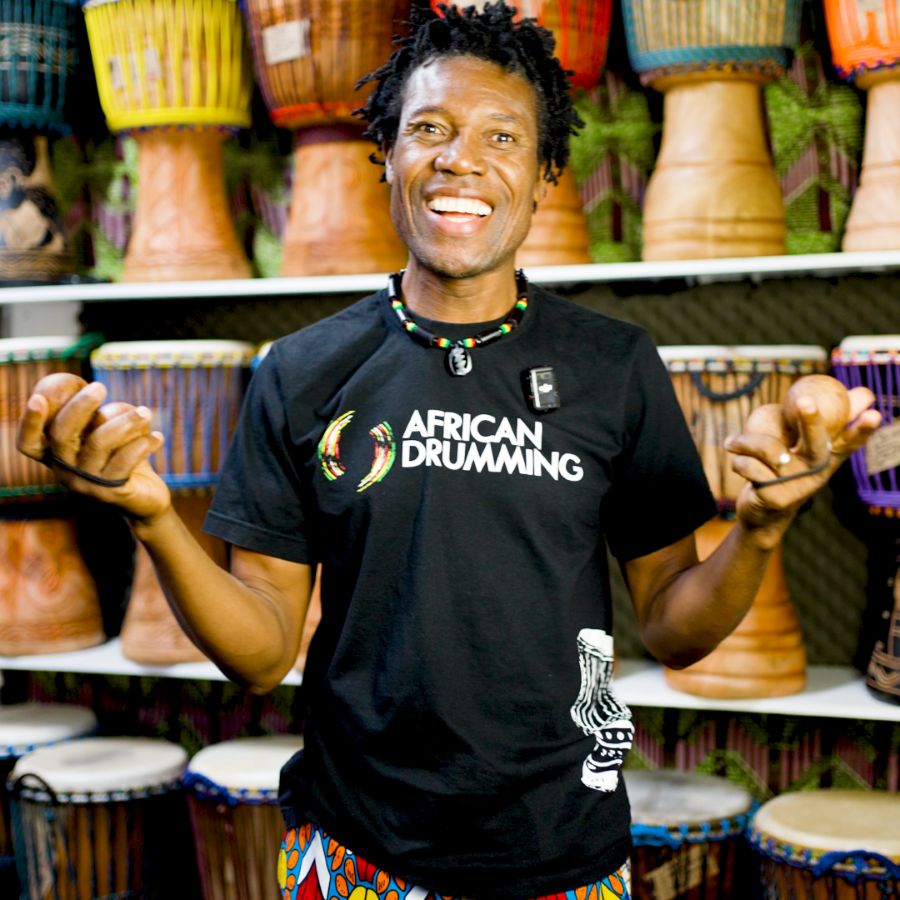 Odai Nmai, African drumming teacher, smiling while playing aslatua during a workshop