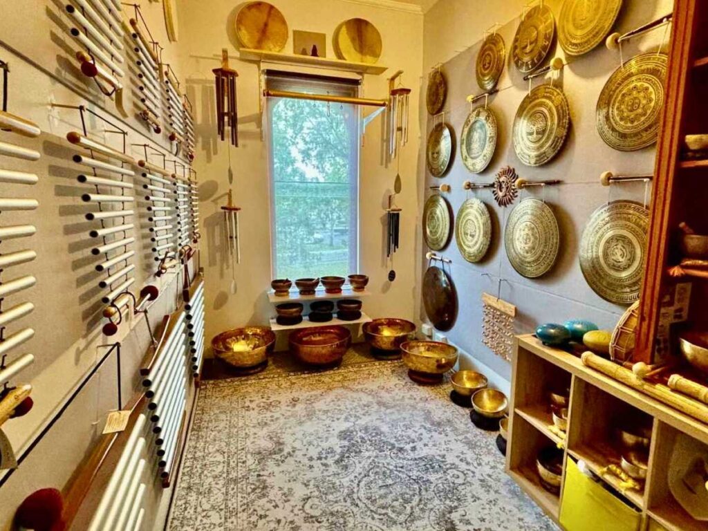 Alt text: Sonora Studio sound healing space for hire in St Kilda, featuring gongs, singing bowls, and chimes displayed on the walls in a calm, softly lit room.