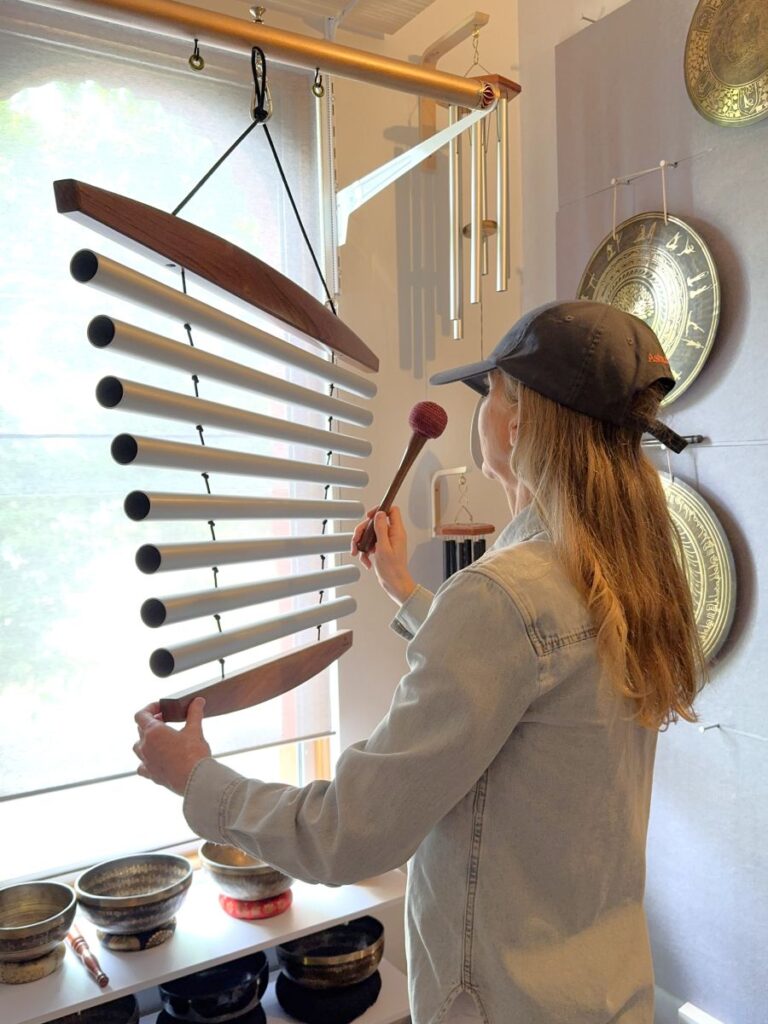 Person playing chimes in the Sonora sound healing studio in St Kilda, surrounded by gongs and singing bowls, available for hire through African Drumming.