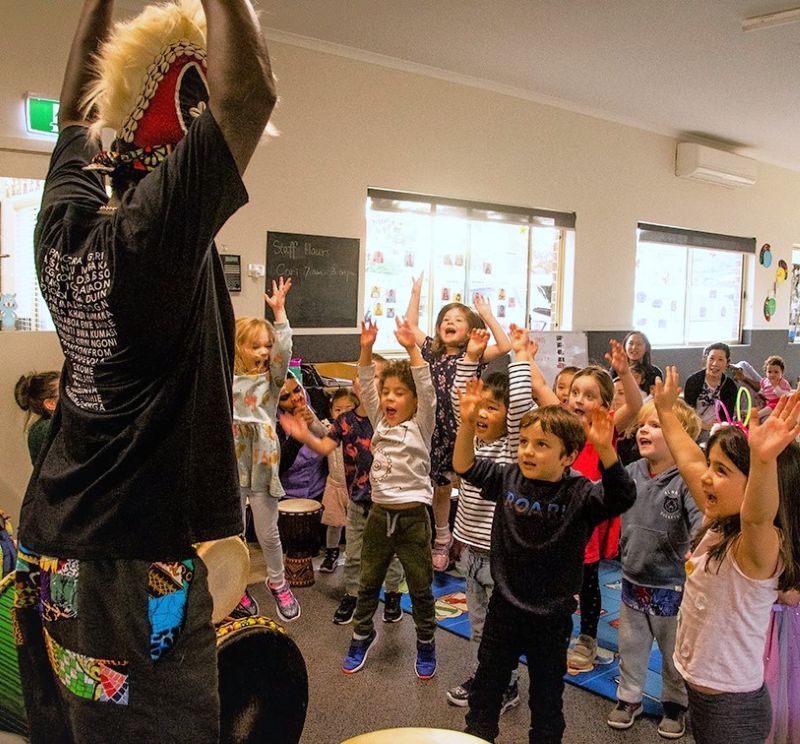Children actively participating in a body percussion workshop, following the movements of the facilitator while enjoying the rhythm.