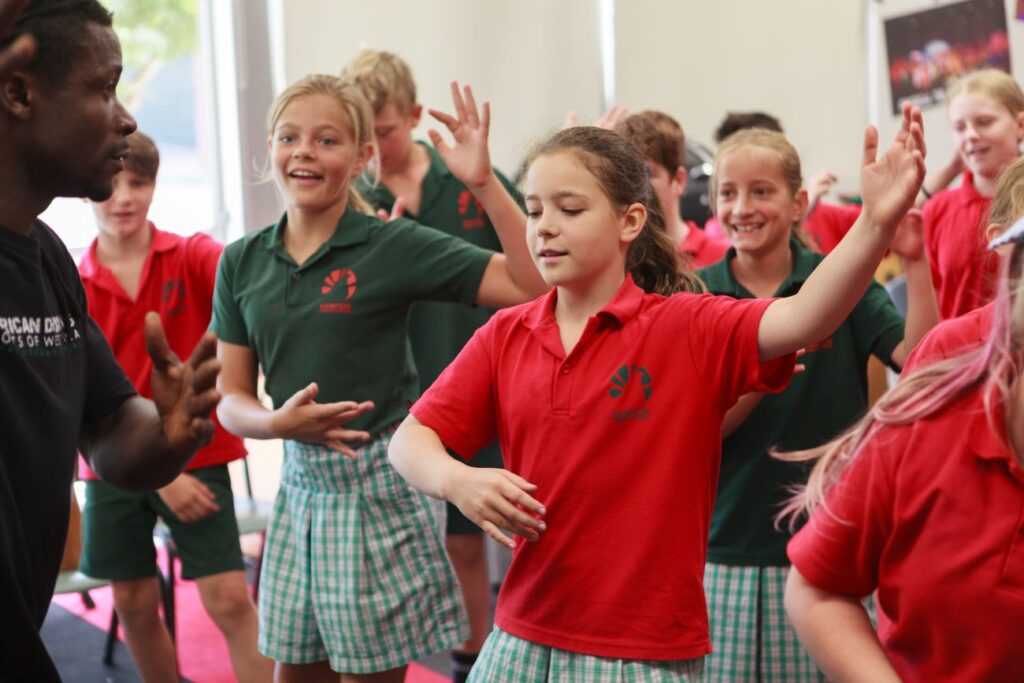 Students engaging in a body percussion workshop, following rhythmic movements with a facilitator.