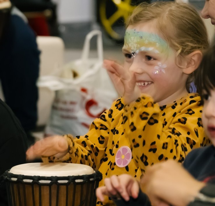 Child playing a djembe during an all abilities drumming workshop