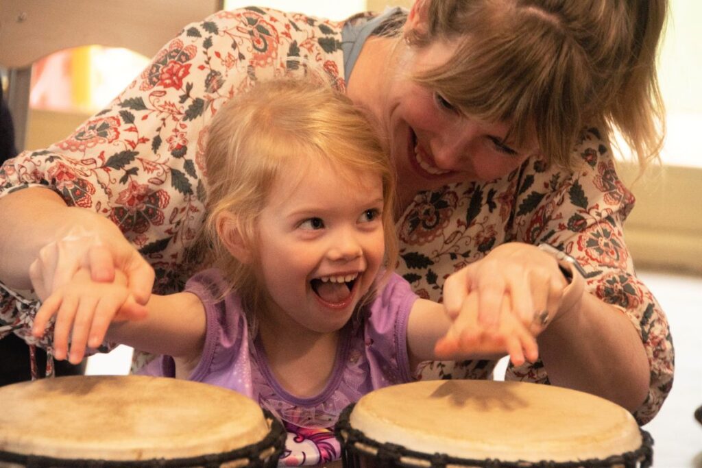 Child and adult drumming together during a mindfulness and wellbeing workshop.