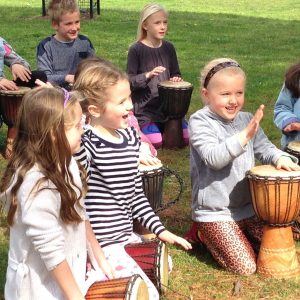 kids enjoying drumming in the park with djembes on the grass