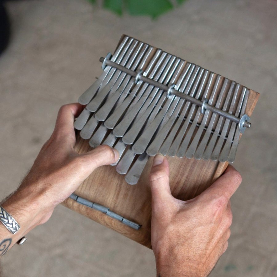 Handmade kalimba with hand-forged metal keys on a wooden body, played with both thumbs