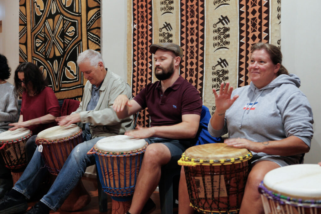 adults sitting together playing djembe